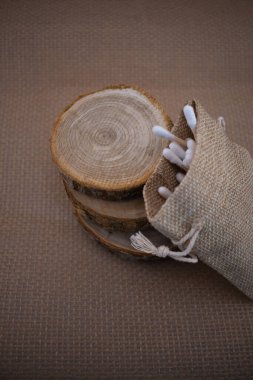 Çuval bezi torbası içinde, ağaç dilimlerinin üzerinde duran bu doğal bambu pamuklu çubuklarla daha yumuşak bir ayak izi kucaklayın. Çevreye duyarlı güzellik ve sürdürülebilir takaslar için mükemmel.