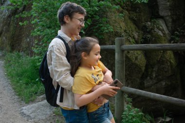Doğada yürek ısıtan bir bağ anı. Açık hava ortamında genç bir erkek ve kız kardeşi birlikte gösteriyor. Kardeş bağı, teknoloji ve paylaşılan anlar için ideal bir tema.