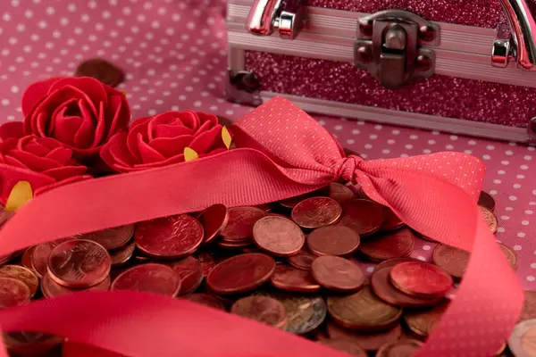 Pembe arka planda bozuk paralarla hediye kutusu