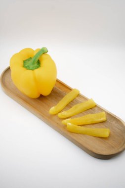 Sarı dolma biber, eşsiz bir şekilde ahşap bir tabanda ışık saçan dilimlerle sunulur, doğal canlılığı ve yenilikçi mutfağı sembolize eder. Mutfak sanatı, diyet ya da yemek ilhamı için ideal.