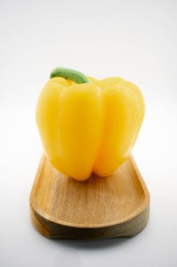 Sarı dolma biber, eşsiz bir şekilde ahşap bir tabanda ışık saçan dilimlerle sunulur, doğal canlılığı ve yenilikçi mutfağı sembolize eder. Mutfak sanatı, diyet ya da yemek ilhamı için ideal.