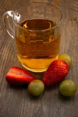 Bir bardak yeşil çay, taze çilek ve sulu üzümler sağlıklı bir hoşgörü ve saflık hissi uyandırıyor. Temiz yemek, sağlıklı yemek tarifleri veya düşünceli yaşam tarzı içeriği için ideal