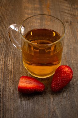 Yakın plan çekimde canlı çileklerin yanında bir bardak yeşil çay, ferahlatıcı bir rahatlık ve doğal tatlılık hissi uyandırıyor. Sağlıklı yaşam, içecek ve yemek blogu içeriği için ideal