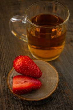 Yakın plan çekimde canlı çileklerin yanında bir bardak yeşil çay, ferahlatıcı bir rahatlık ve doğal tatlılık hissi uyandırıyor. Sağlıklı yaşam, içecek ve yemek blogu içeriği için ideal