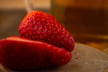 Yakın plan çekimde canlı çileklerin yanında bir bardak yeşil çay, ferahlatıcı bir rahatlık ve doğal tatlılık hissi uyandırıyor. Sağlıklı yaşam, içecek ve yemek blogu içeriği için ideal