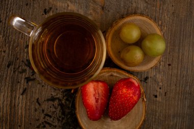 Bir bardak yeşil çay, taze çilek ve sulu üzümler sağlıklı bir hoşgörü ve saflık hissi uyandırıyor. Temiz yemek, sağlıklı yemek tarifleri veya düşünceli yaşam tarzı içeriği için ideal