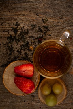 Bir bardak yeşil çay, taze çilek ve sulu üzümler sağlıklı bir hoşgörü ve saflık hissi uyandırıyor. Temiz yemek, sağlıklı yemek tarifleri veya düşünceli yaşam tarzı içeriği için ideal