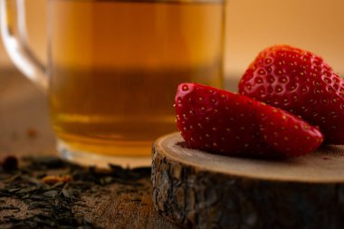 Yakın plan çekimde canlı çileklerin yanında bir bardak yeşil çay, ferahlatıcı bir rahatlık ve doğal tatlılık hissi uyandırıyor. Sağlıklı yaşam, içecek ve yemek blogu içeriği için ideal