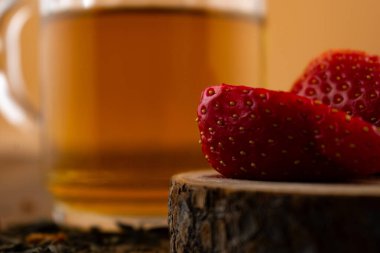 Yakın plan çekimde canlı çileklerin yanında bir bardak yeşil çay, ferahlatıcı bir rahatlık ve doğal tatlılık hissi uyandırıyor. Sağlıklı yaşam, içecek ve yemek blogu içeriği için ideal