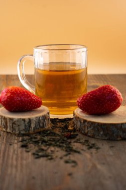 Yakın plan çekimde canlı çileklerin yanında bir bardak yeşil çay, ferahlatıcı bir rahatlık ve doğal tatlılık hissi uyandırıyor. Sağlıklı yaşam, içecek ve yemek blogu içeriği için ideal