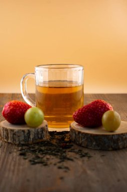 Bir bardak yeşil çay, taze çilek ve sulu üzümler sağlıklı bir hoşgörü ve saflık hissi uyandırıyor. Temiz yemek, sağlıklı yemek tarifleri veya düşünceli yaşam tarzı içeriği için ideal