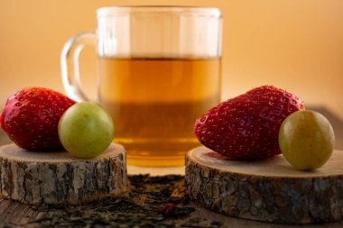 Bir bardak yeşil çay, taze çilek ve sulu üzümler sağlıklı bir hoşgörü ve saflık hissi uyandırıyor. Temiz yemek, sağlıklı yemek tarifleri veya düşünceli yaşam tarzı içeriği için ideal