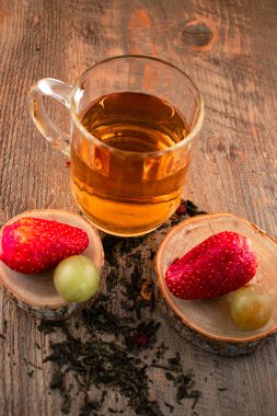 Bir bardak yeşil çay, taze çilek ve sulu üzümler sağlıklı bir hoşgörü ve saflık hissi uyandırıyor. Temiz yemek, sağlıklı yemek tarifleri veya düşünceli yaşam tarzı içeriği için ideal