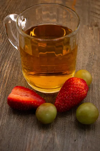 Bir bardak yeşil çay, taze çilek ve sulu üzümler sağlıklı bir hoşgörü ve saflık hissi uyandırıyor. Temiz yemek, sağlıklı yemek tarifleri veya düşünceli yaşam tarzı içeriği için ideal