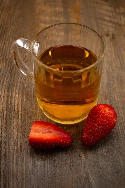 Yakın plan çekimde canlı çileklerin yanında bir bardak yeşil çay, ferahlatıcı bir rahatlık ve doğal tatlılık hissi uyandırıyor. Sağlıklı yaşam, içecek ve yemek blogu içeriği için ideal