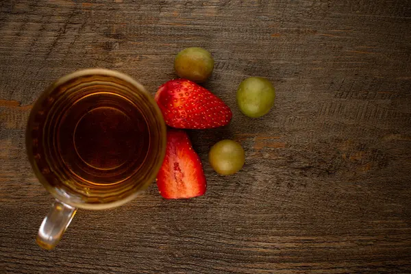Bir bardak yeşil çay, taze çilek ve sulu üzümler sağlıklı bir hoşgörü ve saflık hissi uyandırıyor. Temiz yemek, sağlıklı yemek tarifleri veya düşünceli yaşam tarzı içeriği için ideal