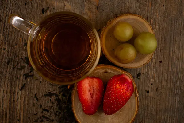 Bir bardak yeşil çay, taze çilek ve sulu üzümler sağlıklı bir hoşgörü ve saflık hissi uyandırıyor. Temiz yemek, sağlıklı yemek tarifleri veya düşünceli yaşam tarzı içeriği için ideal