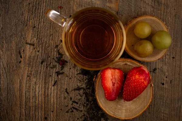 Bir bardak yeşil çay, taze çilek ve sulu üzümler sağlıklı bir hoşgörü ve saflık hissi uyandırıyor. Temiz yemek, sağlıklı yemek tarifleri veya düşünceli yaşam tarzı içeriği için ideal