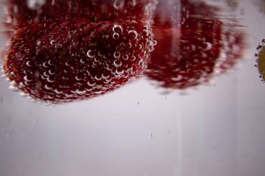 Çilekler ve yeşil üzümler kabarcıklı suya batırılmış, canlandırıcı canlılık ve saf, sağlıklı hoşgörü duyguları uyandırıyor. İçecek, sağlık veya meyve temalı içerik için ideal