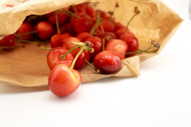 Kırsal kahverengi bir kesekağıdından dökülen kirazlar sağlıklı, taze bir çiftlik zevki ve sürdürülebilir yaşam hissi uyandırıyor. Organik gıda, çiftçi pazarı veya çevre dostu içerik için ideal