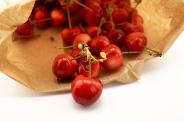 Kırsal kahverengi bir kesekağıdından dökülen kirazlar sağlıklı, taze bir çiftlik zevki ve sürdürülebilir yaşam hissi uyandırıyor. Organik gıda, çiftçi pazarı veya çevre dostu içerik için ideal