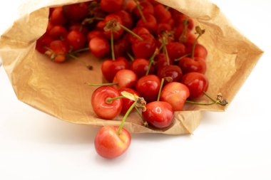 Kırsal kahverengi bir kesekağıdından dökülen kirazlar sağlıklı, taze bir çiftlik zevki ve sürdürülebilir yaşam hissi uyandırıyor. Organik gıda, çiftçi pazarı veya çevre dostu içerik için ideal