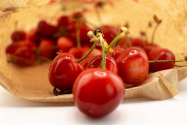 Kırsal kahverengi bir kesekağıdından dökülen kirazlar sağlıklı, taze bir çiftlik zevki ve sürdürülebilir yaşam hissi uyandırıyor. Organik gıda, çiftçi pazarı veya çevre dostu içerik için ideal