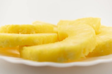 Taze ananas halkaları beyaz bir tabakta güzelce dizilmiş, ferahlatıcı zevkler ve sağlıklı bir hoşgörü hissi uyandırıyor. Sağlıklı atıştırmalıklar, meyve tabakları ya da yaz temalı mutfak malzemeleri için mükemmel.