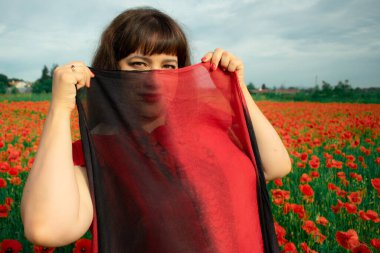 Bir kadın, dalgalı kırmızı ve siyah bir kumaşın üzerinden gizlice bakar. Gizem, cazibe ve doğa ile etkileşim hissini yakalar. Bireysellik ve yaz kaprisleri için idealdir.