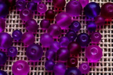 Şeffaf mor ve pembe boncuklardan oluşan renkli bir şelale dokulu bir yüzeyde ışığı yakalıyor, bir sonraki yaratıcı girişimin için hazır. DIY içeriği, mücevher veya soyut arka planlar için harika