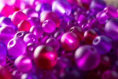 Şeffaf mor ve pembe boncuklardan oluşan renkli bir şelale dokulu bir yüzeyde ışığı yakalıyor, bir sonraki yaratıcı girişimin için hazır. DIY içeriği, mücevher veya soyut arka planlar için harika