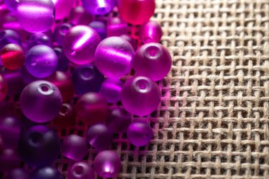 Şeffaf mor ve pembe boncuklardan oluşan renkli bir şelale dokulu bir yüzeyde ışığı yakalıyor, bir sonraki yaratıcı girişimin için hazır. DIY içeriği, mücevher veya soyut arka planlar için harika