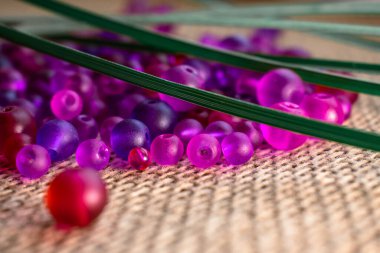 Kırsal bir çuval bezi dokusunda yeşil aksanlı canlı mor boncuklar. Sanat projeleri için mükemmel, DIY, veya sanatsal geçmiş, yaratıcı tasarımlar, mücevherler