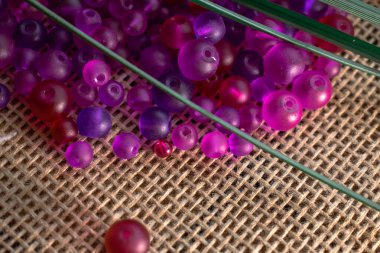 Kırsal bir çuval bezi dokusunda yeşil aksanlı canlı mor boncuklar. Sanat projeleri için mükemmel, DIY, veya sanatsal geçmiş, yaratıcı tasarımlar, mücevherler