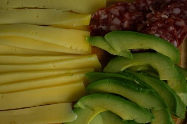Peynir, salam ve avokado ile nefis bir abur cubur tahtası, şık desenli bir bardakla eşleştirilmiş. Yemek blogları için mükemmel, eğlenceli, rahat anlar, evde dinlenme, sosyal toplantılar, ya da hafif yemekler