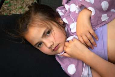 Huzurlu bir çocuk, nazik bir gülümsemeyle, rahat bir şekilde karanlık bir yastıkta kestiriyor. Sıcaklığı, masumiyeti ve derin rahatlığı çağrıştırıyor. Ebeveynlik, Aile, Çocuk Bakımı, Eğitim, Yaşam Tarzı