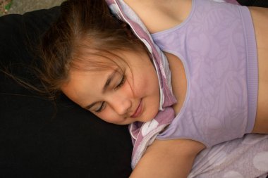 Huzurlu bir çocuk, nazik bir gülümsemeyle, rahat bir şekilde karanlık bir yastıkta kestiriyor. Sıcaklığı, masumiyeti ve derin rahatlığı çağrıştırıyor. Ebeveynlik, Aile, Çocuk Bakımı, Eğitim, Yaşam Tarzı