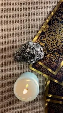 Tarot kartları, mum ışığı ve zar mistik bir sahne yaratır. Bir el zar atar, kaderin temaları, kehanetler ve antik bilgeliği çağrıştırır yumuşak, atmosferik bir ortamda.