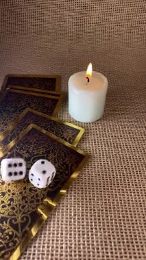 Tarot kartları, mum ışığı ve zar mistik bir sahne yaratır. Bir el zar atar, kaderin temaları, kehanetler ve antik bilgeliği çağrıştırır yumuşak, atmosferik bir ortamda.