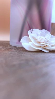 Beyaz kurumuş çiçekli, dikey spa kompozisyonu ve kırsal ahşap üzerinde buzlu difüzyon. Sağlık, doğal güzellik, aromaterapi veya minimalist yaşam tarzı içeriği için idealdir.