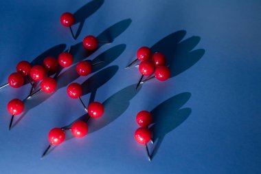 Parlak kırmızı raptiyeler mavi arka plana saçılmış durumda. Bloglar, ofis reklamları, okul içeriği veya verimlilik temaları için mükemmel bir odaklanma, aciliyet ve yaratıcı planlama.