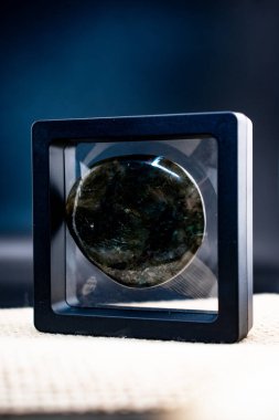 Siyah ve altın aynalı siyah arka planda küçük bir çantada cilalanmış labradorit değerli taş. Mavi-yeşil yanardağı lüksü, maneviyatı ve modern doğal dekoru çağrıştırıyor.