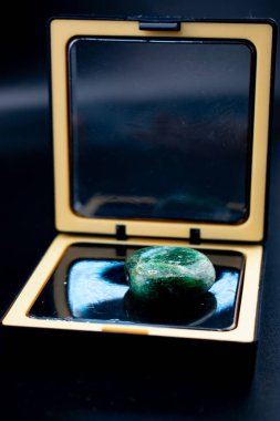 Kırsal bir dal kürenin yanında, siyah ve altın aynalı bir kutuya parafinli yeşil taştan yapılmış bir taş. Karanlık, zarif bir hayat meditasyon, sağlık, doğal dekor veya lüks yaşam tarzı kavramları için idealdir.