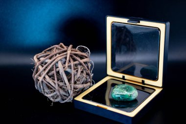 Kırsal bir dal kürenin yanında, siyah ve altın aynalı bir kutuya parafinli yeşil taştan yapılmış bir taş. Karanlık, zarif bir hayat meditasyon, sağlık, doğal dekor veya lüks yaşam tarzı kavramları için idealdir.