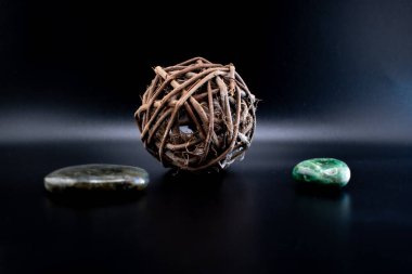 Cilalanmış labradorit ve siyah bir yüzey üzerinde kırsal dal küreli yeşil yeşim taşı. Huzurlu, doğal bir kompozisyon refah, meditasyon ve doğadan esinlenilmiş tasarımlar için idealdir.