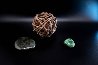 Cilalanmış labradorit ve siyah bir yüzey üzerinde kırsal dal küreli yeşil yeşim taşı. Huzurlu, doğal bir kompozisyon refah, meditasyon ve doğadan esinlenilmiş tasarımlar için idealdir.