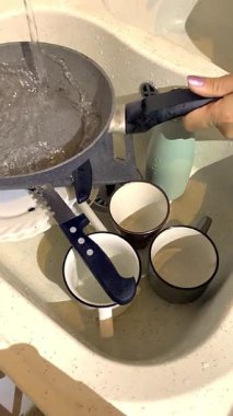 Kirli bulaşıklar, akan suyun altındaki bir lavaboda yıkanmayı bekliyor. Ev işleri, günlük rutin işler ya da temizlik dersleri için mükemmel.
