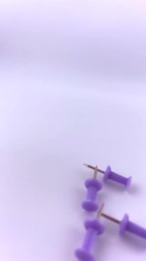 Beyaz bir yüzeye saçılmış mor raptiyeler. Canlı kontrastlı minimalist düz yatak. Üretkenlik görselleri, planlama temaları veya okulla ilgili tasarımlar için mükemmel