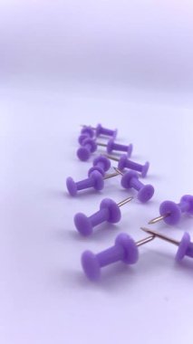 Beyaz bir yüzeye saçılmış mor raptiyeler. Canlı kontrastlı minimalist düz yatak. Üretkenlik görselleri, planlama temaları veya okulla ilgili tasarımlar için mükemmel