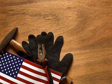Siyah iş eldivenleri, çekiç ve Amerikan bayrağı olan ahşap bir arka plan. Sahne, ABD 'deki İşçi Bayramı' nı temsil ediyor. Yüksek kalite fotoğraf